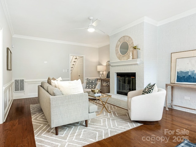 living room with a fireplace, ornamental molding, dark hardwood / wood-style floors, and ceiling fan