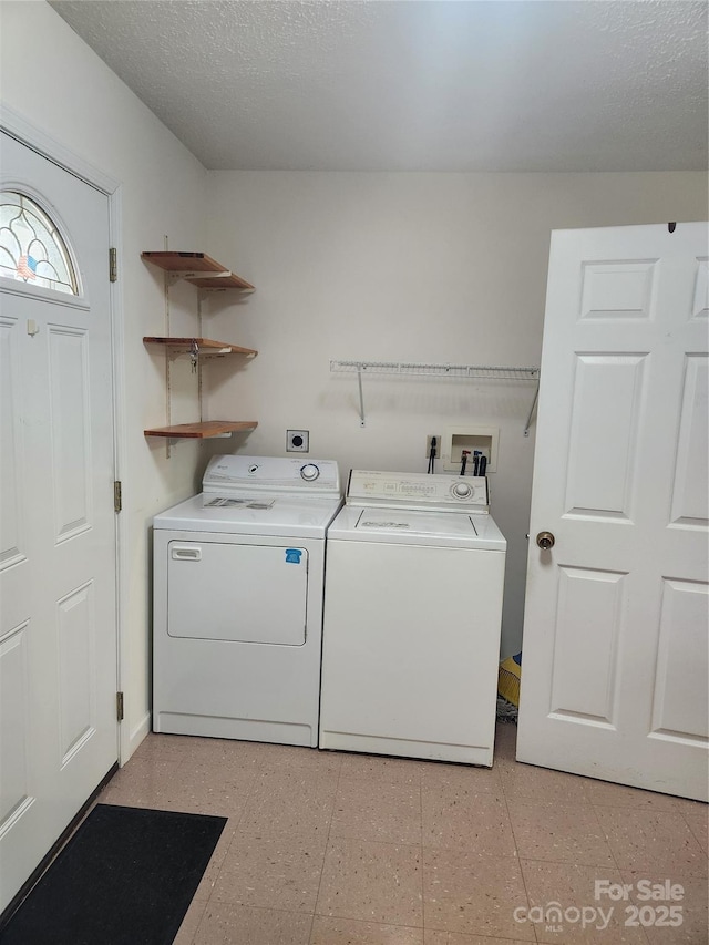 laundry room featuring washer and clothes dryer and a textured ceiling