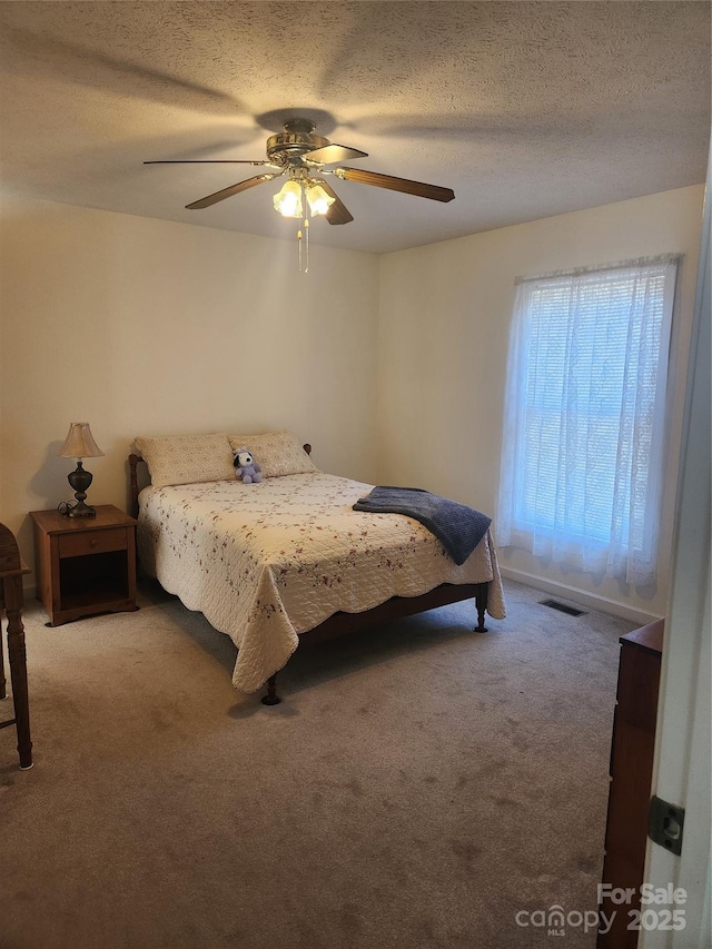 bedroom with carpet floors, ceiling fan, and a textured ceiling