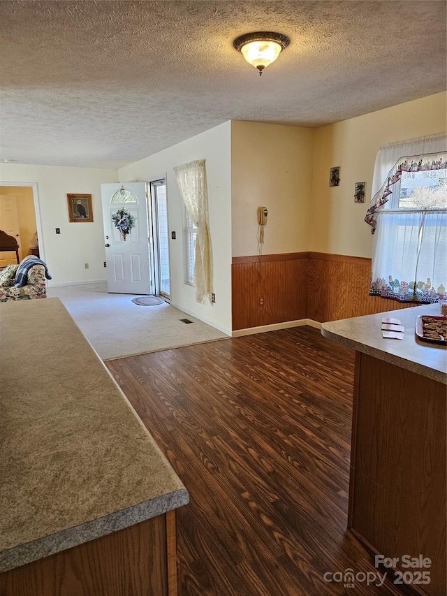 entryway featuring visible vents, dark wood-type flooring, wainscoting, wood walls, and a textured ceiling