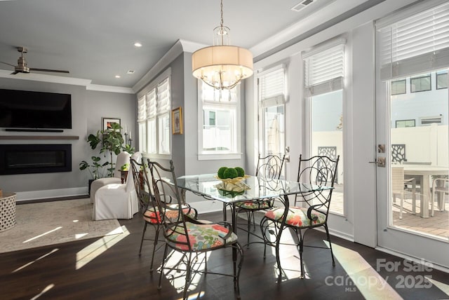 dining area featuring ceiling fan with notable chandelier, crown molding, and dark hardwood / wood-style floors