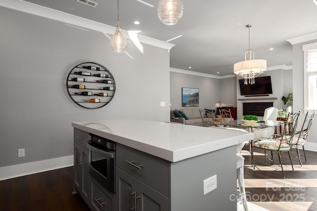 kitchen featuring gray cabinetry, ornamental molding, dark wood-type flooring, oven, and decorative light fixtures