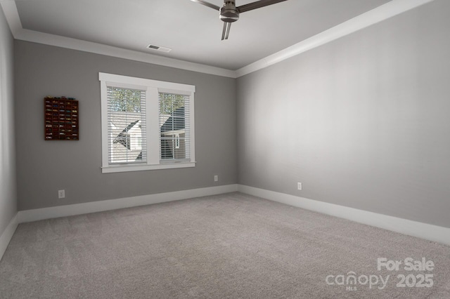 empty room with ceiling fan, crown molding, and carpet