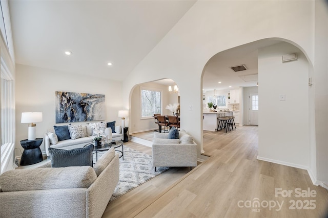 living room with light hardwood / wood-style floors, plenty of natural light, and high vaulted ceiling