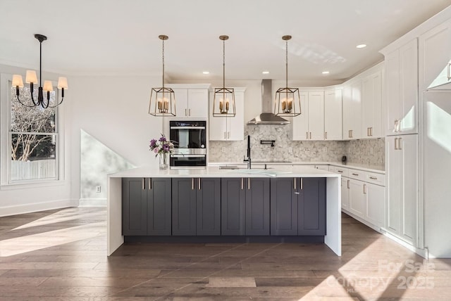 kitchen featuring white cabinets, wall chimney exhaust hood, and hanging light fixtures