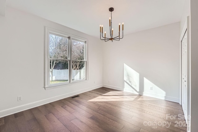 unfurnished dining area featuring dark hardwood / wood-style floors and an inviting chandelier