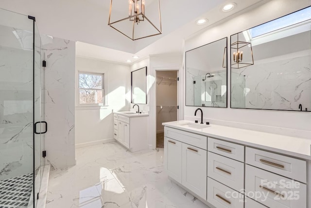 bathroom with a chandelier, vanity, a skylight, and a shower with door