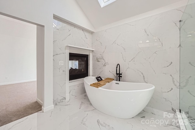 bathroom with vaulted ceiling with skylight and a bathtub