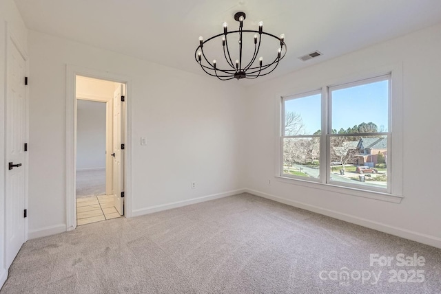 carpeted spare room featuring an inviting chandelier