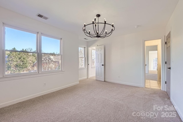 carpeted empty room with an inviting chandelier