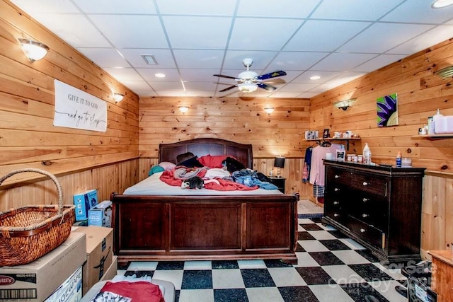 bedroom featuring ceiling fan and wooden walls