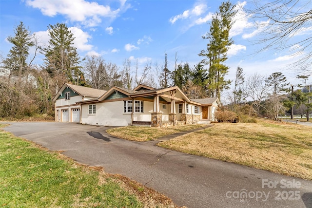 view of front of home featuring covered porch, a front lawn, and a garage