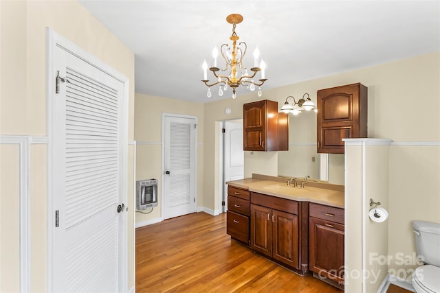 kitchen featuring sink, light wood-type flooring, heating unit, hanging light fixtures, and a chandelier