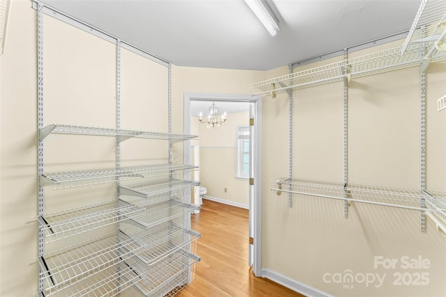 walk in closet featuring a notable chandelier and hardwood / wood-style floors