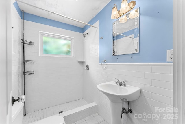 bathroom with tile walls, a tile shower, and toilet