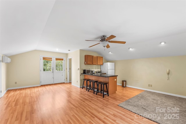 kitchen with light hardwood / wood-style flooring, white fridge, vaulted ceiling, and a wall unit AC