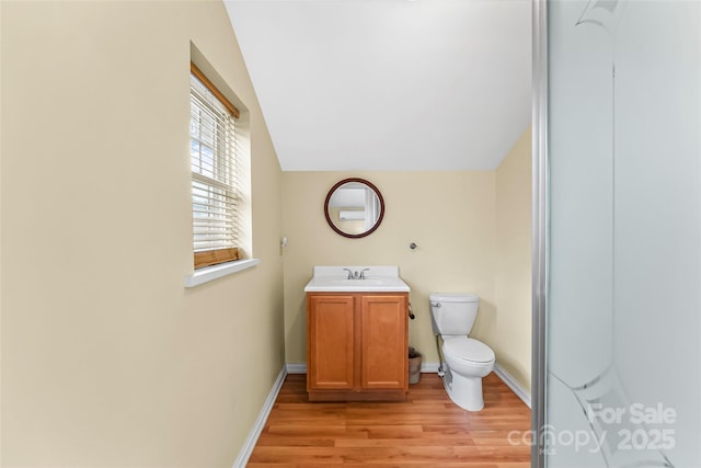 bathroom with toilet, vanity, lofted ceiling, and hardwood / wood-style flooring