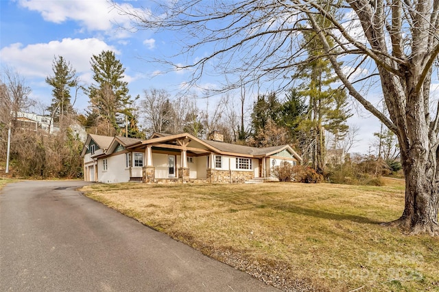 view of front of property featuring covered porch, a garage, and a front yard