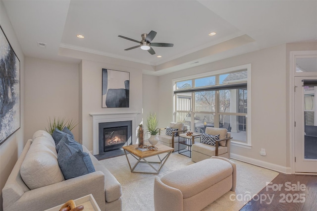 living room featuring ceiling fan, light hardwood / wood-style floors, and a tray ceiling