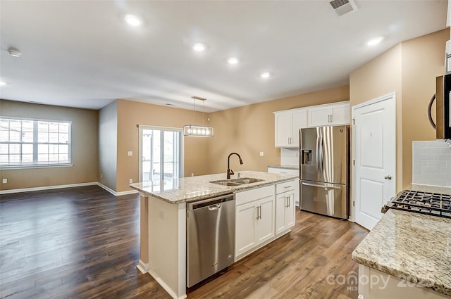 kitchen featuring white cabinets, pendant lighting, appliances with stainless steel finishes, and a center island with sink