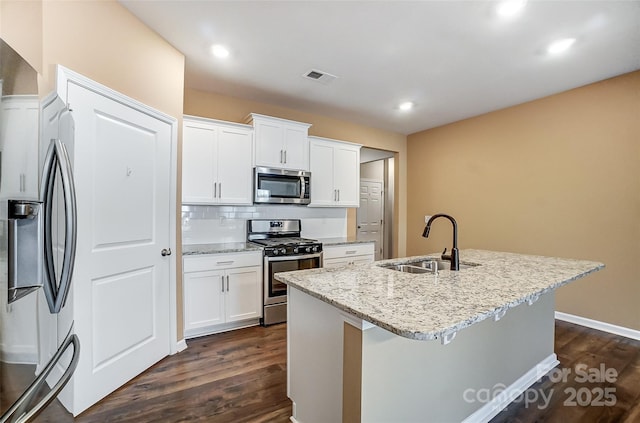 kitchen with white cabinets, appliances with stainless steel finishes, sink, and an island with sink