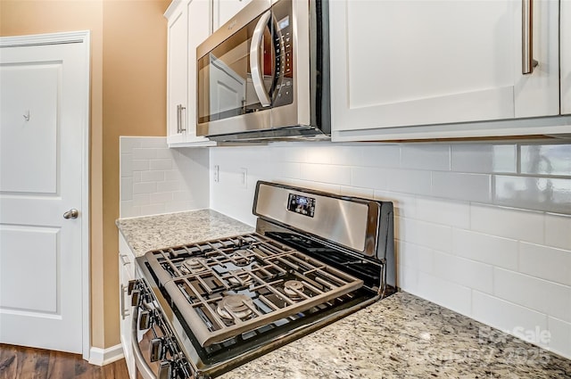 kitchen with white cabinets, decorative backsplash, appliances with stainless steel finishes, and light stone counters