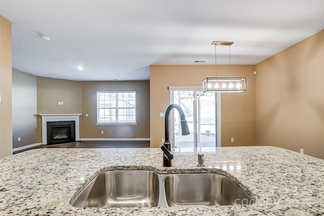 kitchen with sink, light stone counters, and pendant lighting