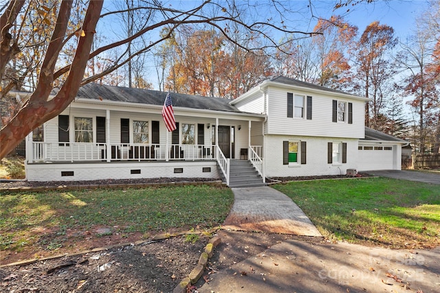 tri-level home featuring covered porch, a garage, and a front lawn