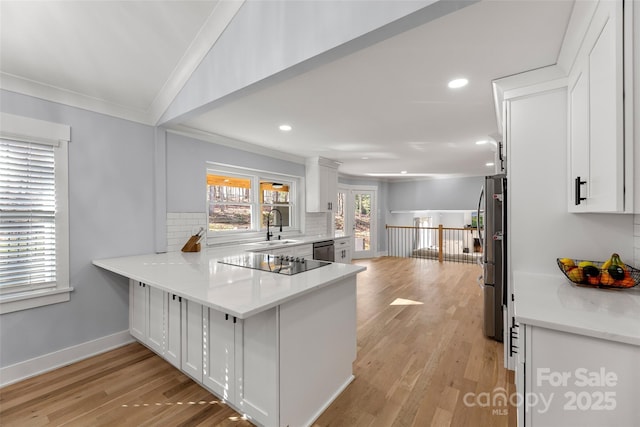 kitchen featuring kitchen peninsula, stainless steel appliances, ornamental molding, white cabinets, and sink