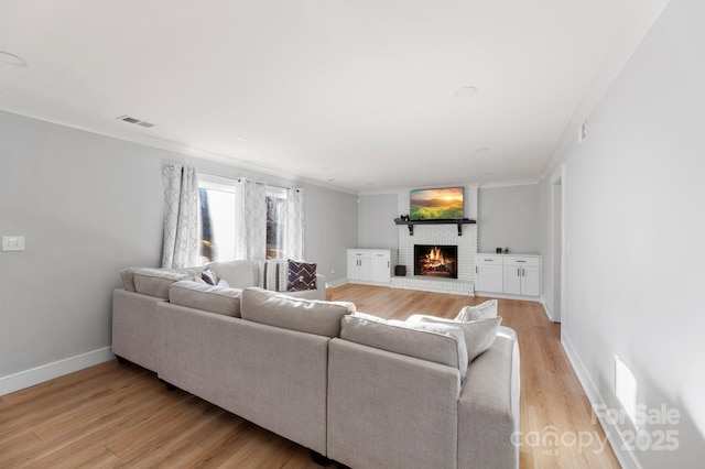 living room featuring light wood-type flooring, a fireplace, and crown molding