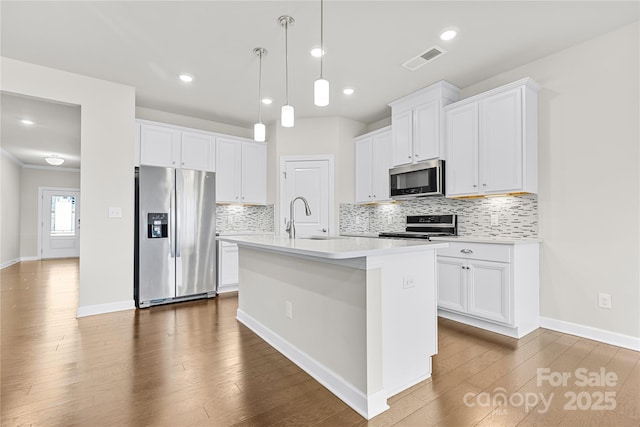 kitchen featuring sink, white cabinets, stainless steel appliances, and an island with sink