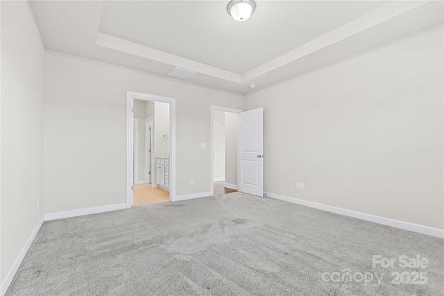 unfurnished room featuring light colored carpet and a raised ceiling