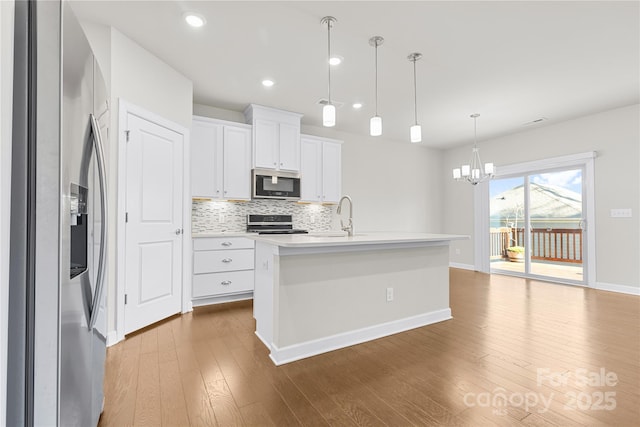 9307 Dufaux Dr, Charlotte, NC 28278 - kitchen featuring tasteful backsplash, baseboards, a notable chandelier, stainless steel appliances, and dark wood-type flooring