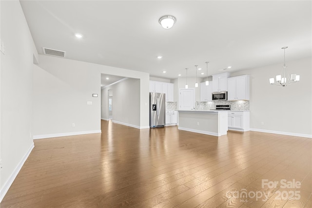 9307 Dufaux Dr, Charlotte, NC 28278 - unfurnished living room with visible vents, wood-type flooring, an inviting chandelier, baseboards, and recessed lighting