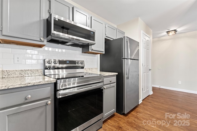 kitchen featuring tasteful backsplash, appliances with stainless steel finishes, light hardwood / wood-style flooring, and gray cabinetry