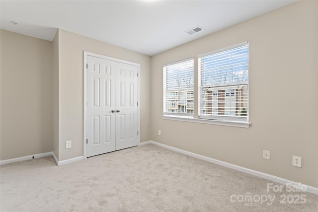 unfurnished bedroom with light colored carpet and a closet