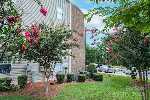 view of side of property featuring central AC and a yard