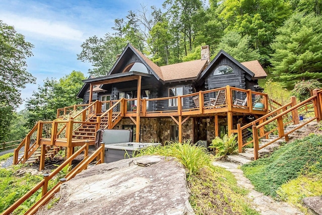 rear view of house with a deck and a hot tub