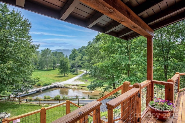 wooden terrace with a yard and a water view