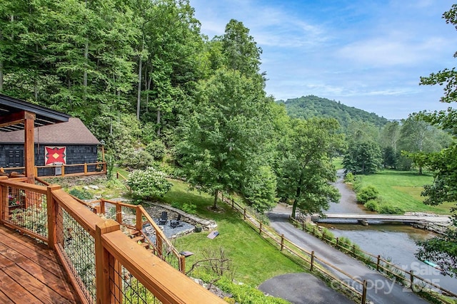 wooden terrace with a water view and a yard