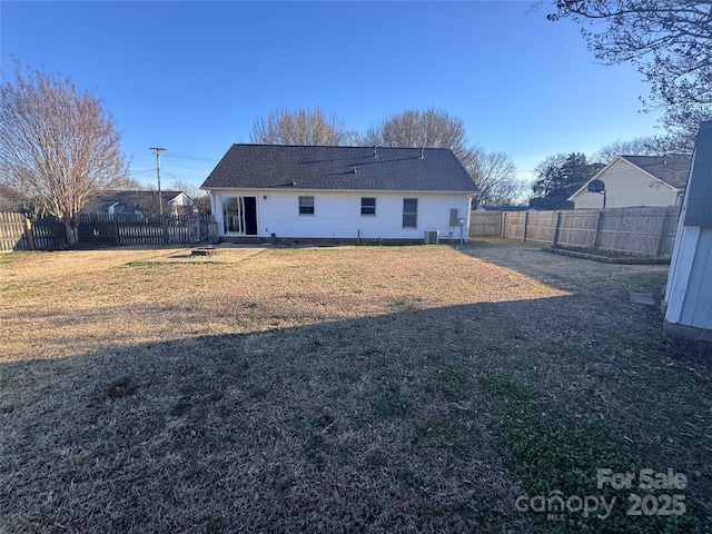 rear view of property featuring central AC and a lawn