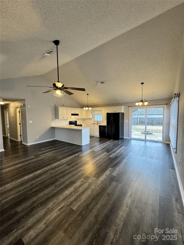 unfurnished living room featuring lofted ceiling, dark hardwood / wood-style flooring, and ceiling fan with notable chandelier