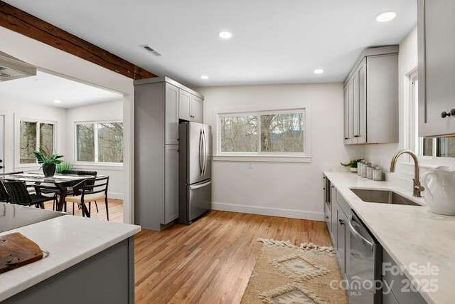 kitchen with light wood-type flooring, appliances with stainless steel finishes, gray cabinetry, and sink