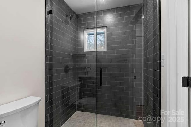 bathroom with a shower with shower door and toilet