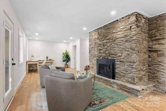 living room with light wood-type flooring and a stone fireplace