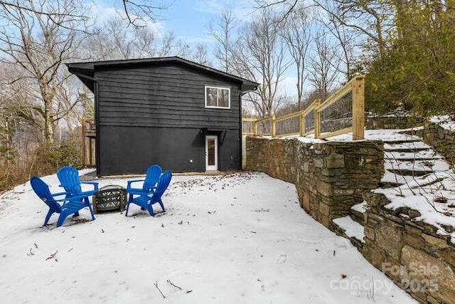 snow covered rear of property with an outdoor fire pit