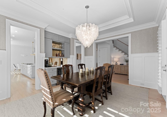 dining area featuring ornamental molding, beverage cooler, light hardwood / wood-style floors, and a chandelier