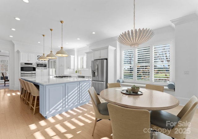 dining room featuring a chandelier, ornamental molding, and light hardwood / wood-style flooring