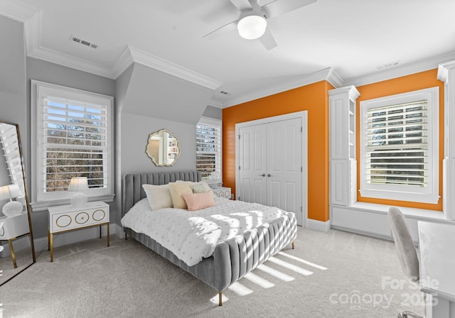 carpeted bedroom with multiple windows, a closet, ceiling fan, and ornamental molding