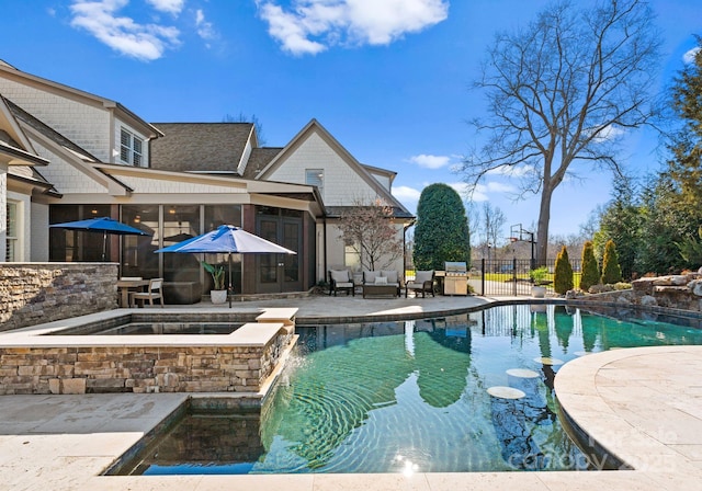 view of pool with a sunroom, a patio, pool water feature, and an in ground hot tub